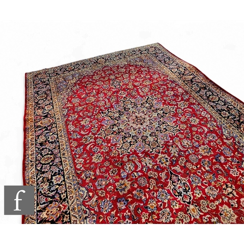 569 - A large Persian Najafabad style carpet, the red central medallion with floral designs, within blue a... 