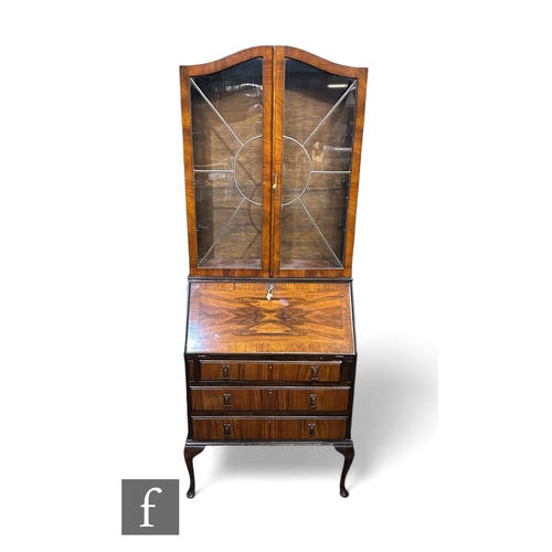 1088 - A late 1930s figured walnut bureau bookcase, enclosed by a sunburst pair of leaded light doors, over... 