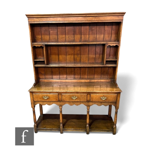 1100 - An 18th Century style oak dresser, fitted with three frieze drawers above a shaped apron on turned b... 