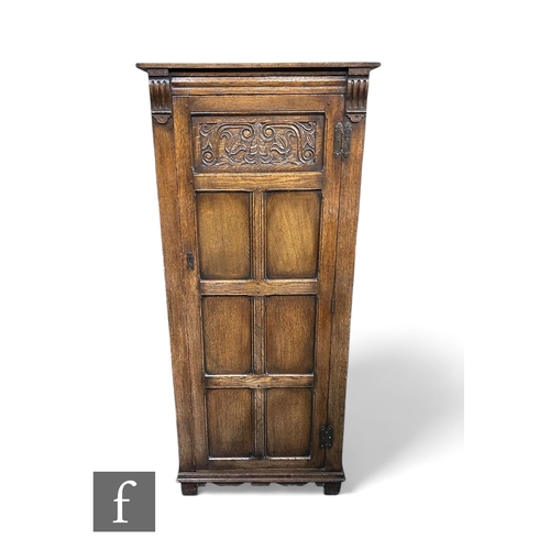 1098 - A small 1930s oak hall wardrobe enclosed by a carved panel door below a fluted cornice and capital m... 