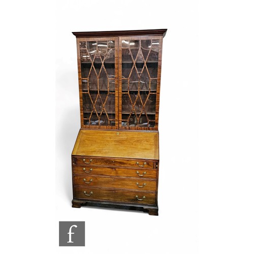 1071 - A George III mahogany bureau bookcase enclosed by a pair of bar glazed doors below a projecting moul... 