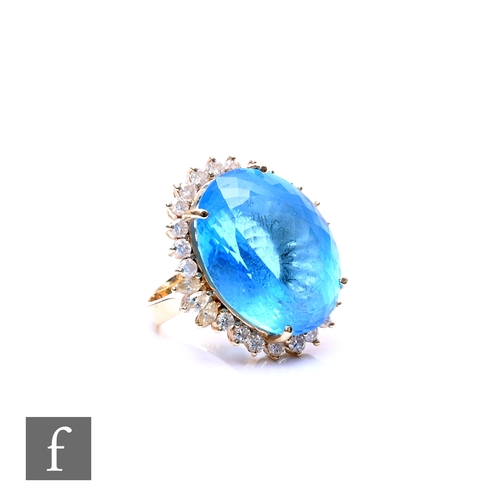 72 - A 14ct blue topaz and diamond cluster ring, central oval topaz, length 22mm, within a border of bril... 