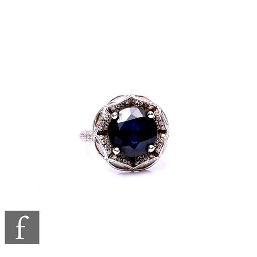 73 - An 18ct white gold sapphire and diamond cluster ring, central circular sapphire, weight 6ct, within ... 