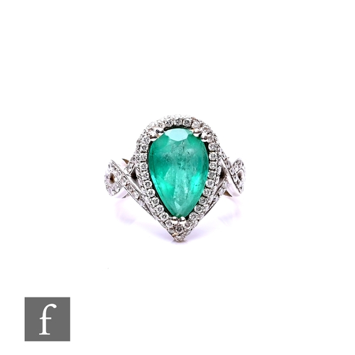 74 - An 18ct white gold emerald and diamond cluster ring, central pear shaped emerald, length 13mm, withi... 