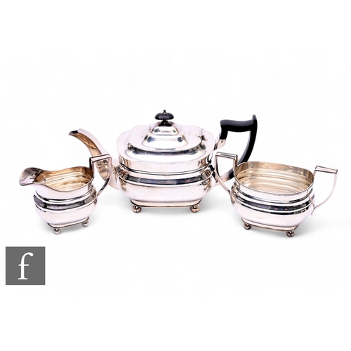 447 - An early 20th Century three-piece boat-shaped silver tea service raised to ball feet, the teapot wit... 