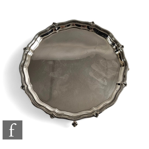 432 - A George V silver hallmarked salver of plain circular form having a pie crust edge and supported on ... 