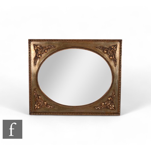 818 - A 20th Century oval wall mirror within a beaded edge and rectangular gilt frame, 88cm x 72cm.