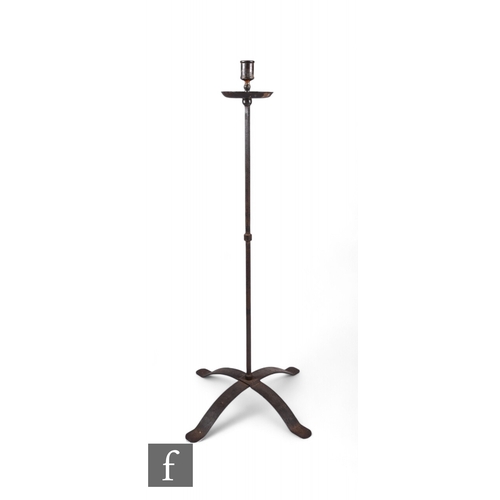 841 - A wrought iron floor standing candlestick, with circular shaped drip tray over a strapwork cruciform... 