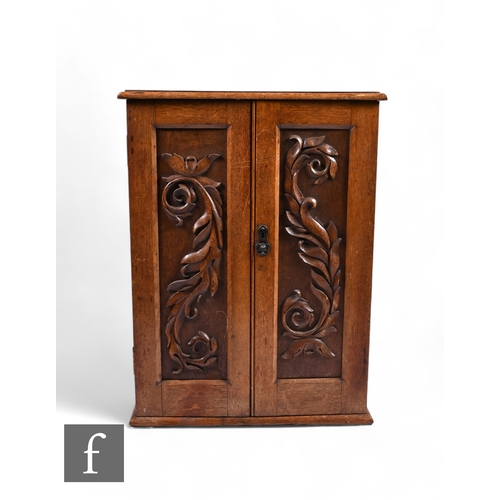 857 - An Edwardian oak cupboard, the fitted shelf interior enclosed by a pair of carved panel doors below ... 