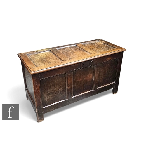 858 - An 18th century oak coffer, the plain panel front below a conforming hinged top on stiles, height 69... 