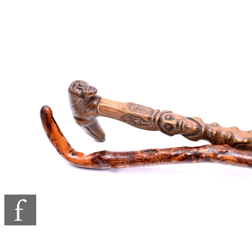 587 - Two folk art walking sticks, one carved with mask sections below a beast handle and the other root w... 