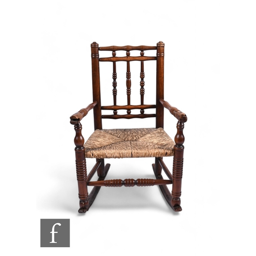 864 - A late 18th to early 19th Century child's fruitwood rocking chair, with turned spindle frame and wov... 