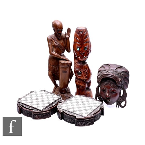 461 - A 20th Century carved African figure playing a drum, a totem style figure, a carved wall mask and a ... 