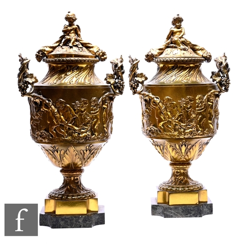 506 - A pair of 19th Century brass urns and covers of classical form decorated in raised relief with amori... 