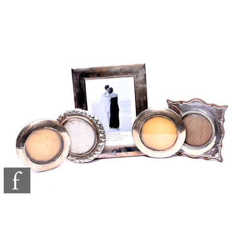 396 - Four early 20th Century hallmarked silver easel photograph frames, one decorated with leaf border, v... 