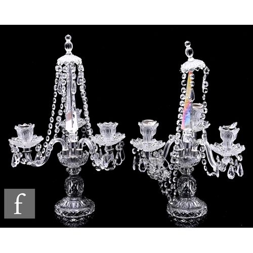 230 - A pair of pressed glass three light candelabra in the manner of Baccarat with a pedestal base rising... 