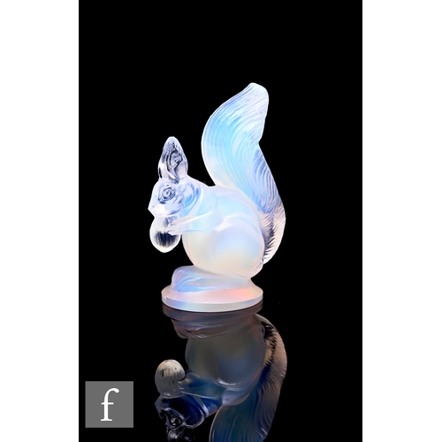 270 - A small 1930s Art Deco opalescent figure of a seated squirrel holding a nut, raised to a circular ba... 