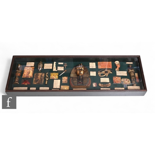 598 - A display case containing replica Tutankhamen relics and objects, 33cm x 106cm.