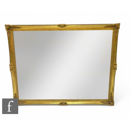 870 - A large 20th Century gilt bevelled edge wall mirror, scroll floral frame, 136cm x 105cm.