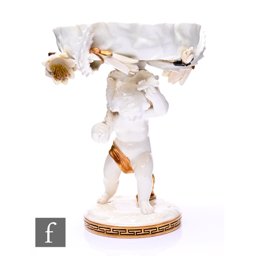 192 - A late 19th Century Moore Brothers pedestal taza modelled as a putti figure carrying a frill rim bow... 