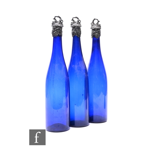 342 - A set of three 19th Century slender bottle form decanters in dark 'Bristol Blue' with applied fruiti... 