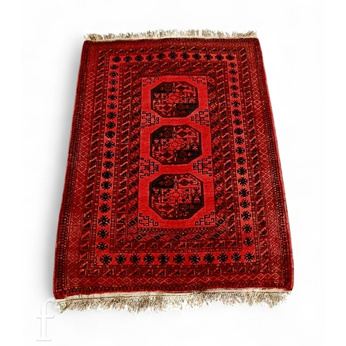 1150 - A 20th Century Afghan style rug, a row of three lozenges on a red ground, within multi border, 192cm... 