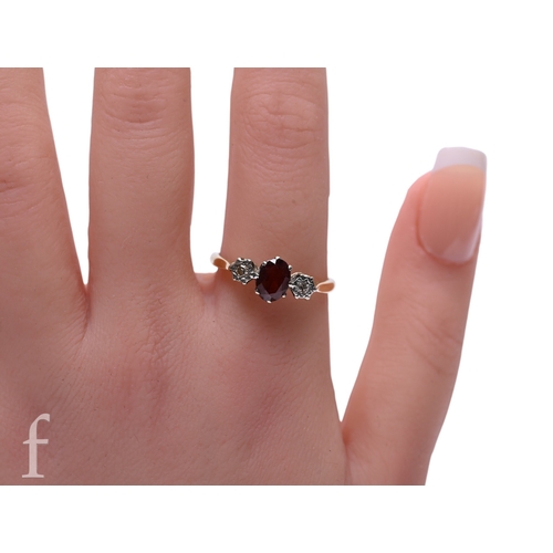 52 - An 18 carat gold diamond and red stone three stone ring, the central stone flanked by two brilliant ... 