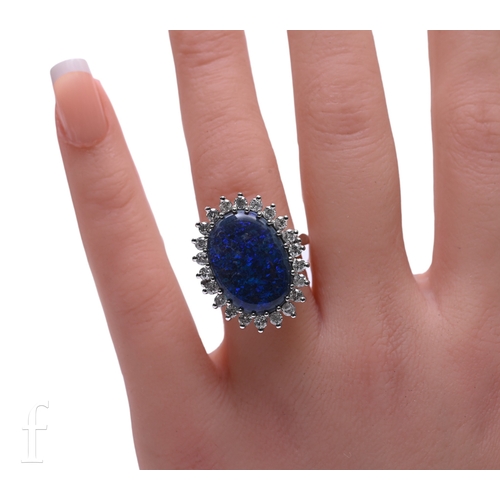 19 - A black opal and diamond ring, the oval cabochon opal within a diamond set bezel, low basket set on ... 