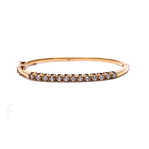 34 - A diamond bangle, the thirteen brilliant-cut diamonds claw set within an undulating border, to a sol... 