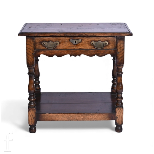 740 - An 18th Century style oak side table fitted with a single drawer, brass drop handles, on turned legs... 