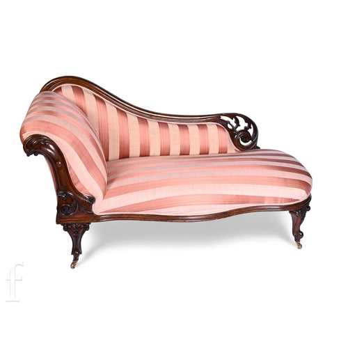 753 - A Victorian mahogany framed and carved chaise longue, scroll arm on cabriole legs and castors, uphol... 