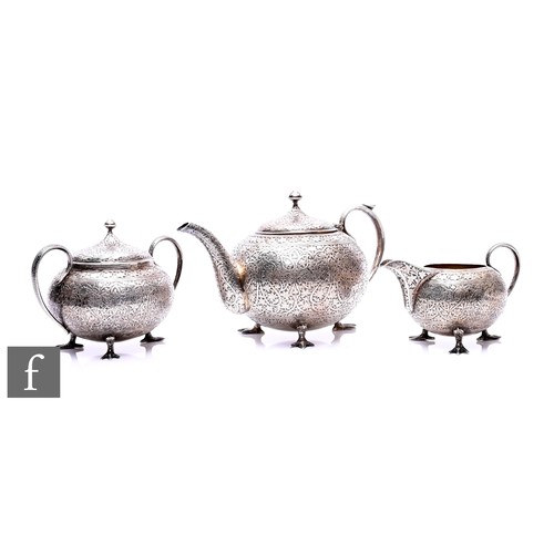 An early 20th Century Indian silver three-piece tea service, possibly Kashmir, comprising teapot, milk jug and sugar bowl, all engraved with scrolling foliate and arabesque designs, raised on chicken foot supports, with snake handles, approximately 33ozt, slight damage