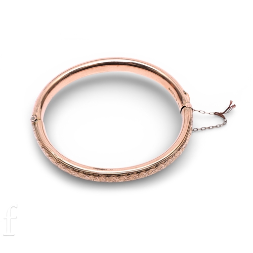 25 - An Edwardian 9 carat gold bangle, the hinged mount with engraved ivy leaf decoration to the upper se... 