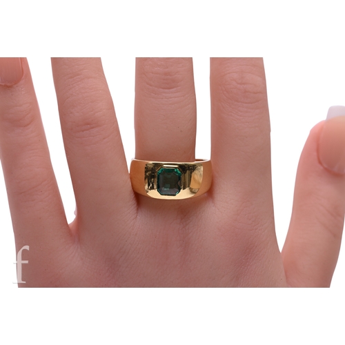 47 - An emerald and gold ring, cut-cornered emerald-cut emerald inset into a broad 18 carat gold band.