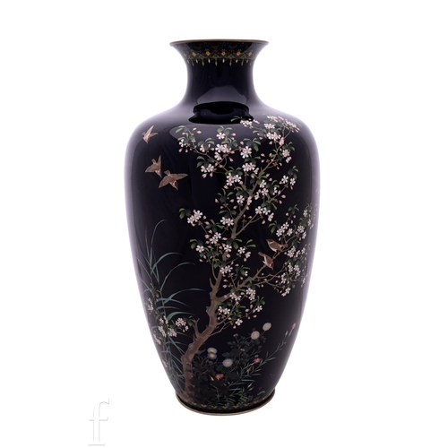 A Japanese Hayashi Kodenji Meiji period (1868-1912) cloisonne enamel vase, the deep blue mirror ground picked out with flowering blossom trees, birds in flight within an intricate trellis and lappet work border, lozenge seal mark of Hayashi Kodenji (1831-1915), Hayashi Kodenji workshop to base, height 30cm.