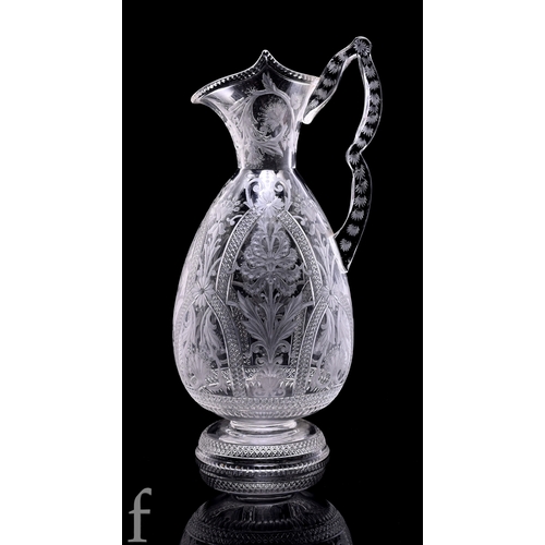 A late 19th Century clear crystal claret jug attributed to Thomas Webb & Sons, the tapered ovoid body with a flared collar neck and pulled rim with a double arched handle, the body cut, polished, engraved and intaglio decorated in the manner of Dr Christopher Dresser with repeat stylised flowers and foliage within Gothic arched panels with matched decoration to the neck, handle and foot, unmarked, height 27.5cm.