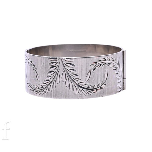 58 - A silver bangle, the broad bangle engraved with ferns against a satin finish, concealed clasp, hallm... 