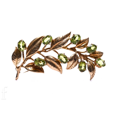 164 - A peridot and 9 carat gold spray brooch, the nine oval mixed-cut peridots, claw set on a branch with... 