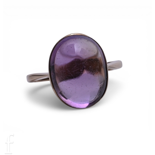 138 - An amethyst set ring, the oval cabochon-cut amethyst collet set above a plain band, unmarked, total ... 