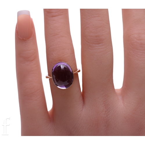 138 - An amethyst set ring, the oval cabochon-cut amethyst collet set above a plain band, unmarked, total ... 