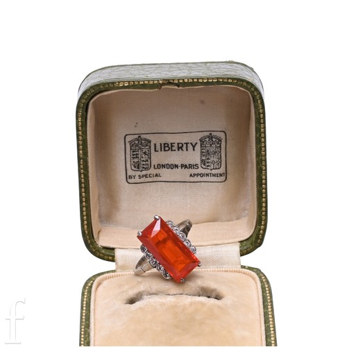 181 - Liberty & Co; a fire opal ring, circa 1900, the step-cut fire opal, four claw set between diamon... 