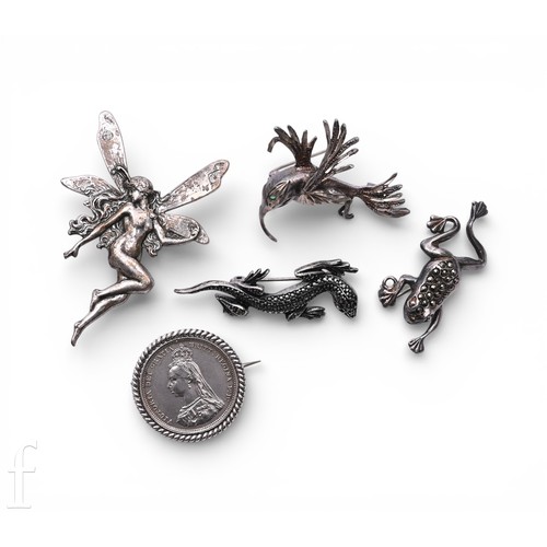 19 - A silver mounted 1887 shilling brooch, and four further unmarked white metal brooches to include Hum... 