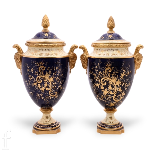 845 - A pair of Coalport pedestal vases, the shield shape body with applied rams head mask handles below a... 