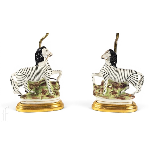 824 - A pair of 19th Century Staffordshire chimney ornaments, each modelled as a zebra on naturalistic bas... 