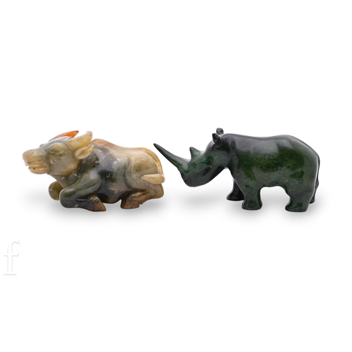 1324 - A 20th Century carved green hardstone model of a rhino and another of a seated bull on a stand. (2)