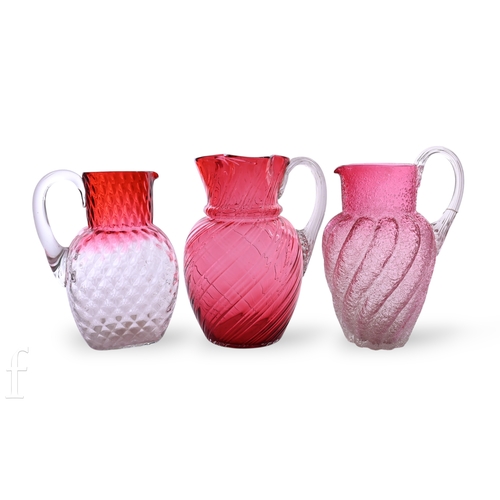 1183 - A late 19th Century cranberry glass jug, the wrythen fluted body rising to quatrelobed rim, applied ... 