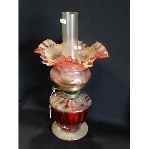 18 - A Circular Based Cranberry Glass Oil Lamp With Cranberry Tinted Shade