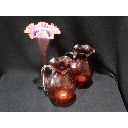 65 - A Pair Of Cranberry Glass Handled Jugs, Together With A Pink Tinted Vase