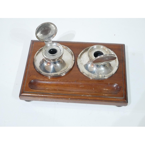 402a - AN EARLY 20TH CENTURY SILVER AND MAHOGANY DESK INKSTAND
Two spherical inkwells on a fitted mahogany ... 