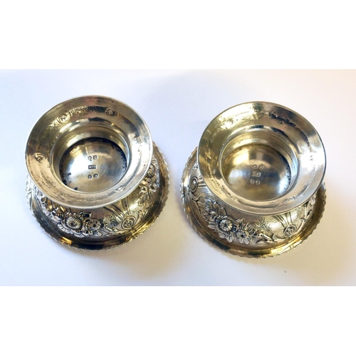 442 - A PAIR OF GEORGIAN SILVER CIRCULAR SALTS 
With embossed floral decoration and flared foot rim, hallm... 